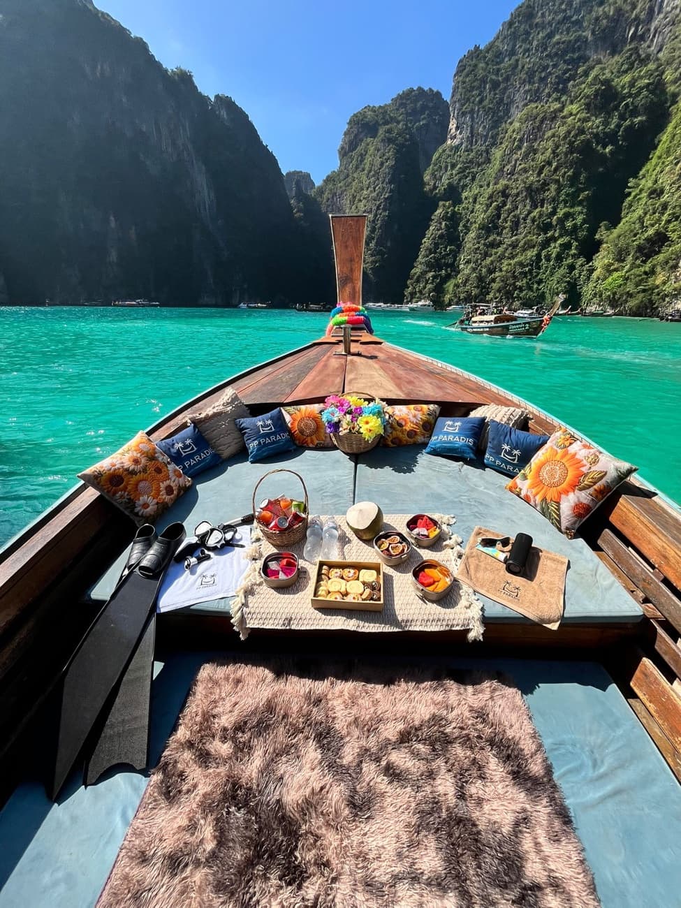 Notre long-tail privé PP Paradise dressé pour la journée — coussins, fruits frais, lagon turquoise de Phi Phi Leh